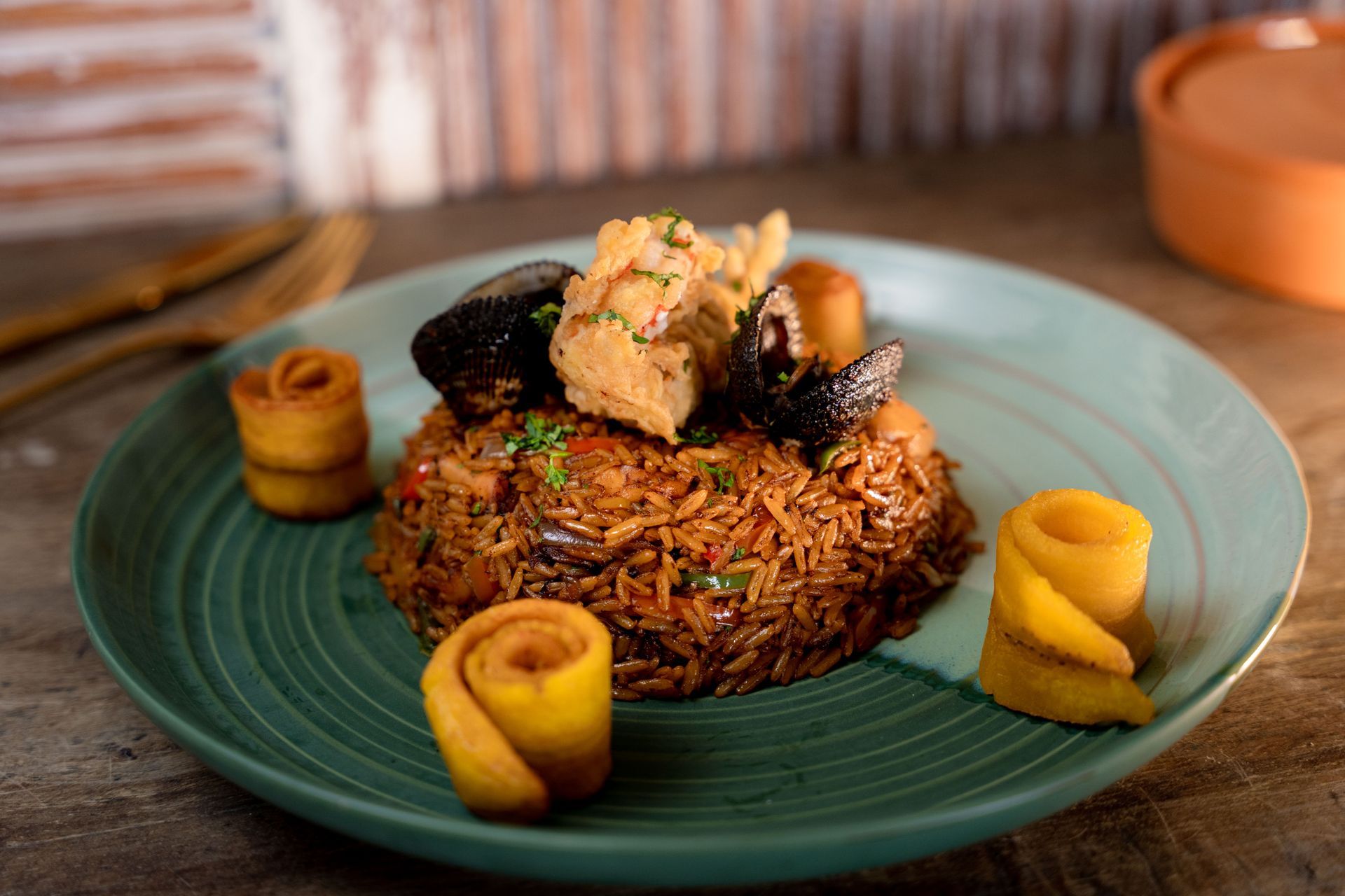 Seafood rice dish with fried plantains on a teal plate.