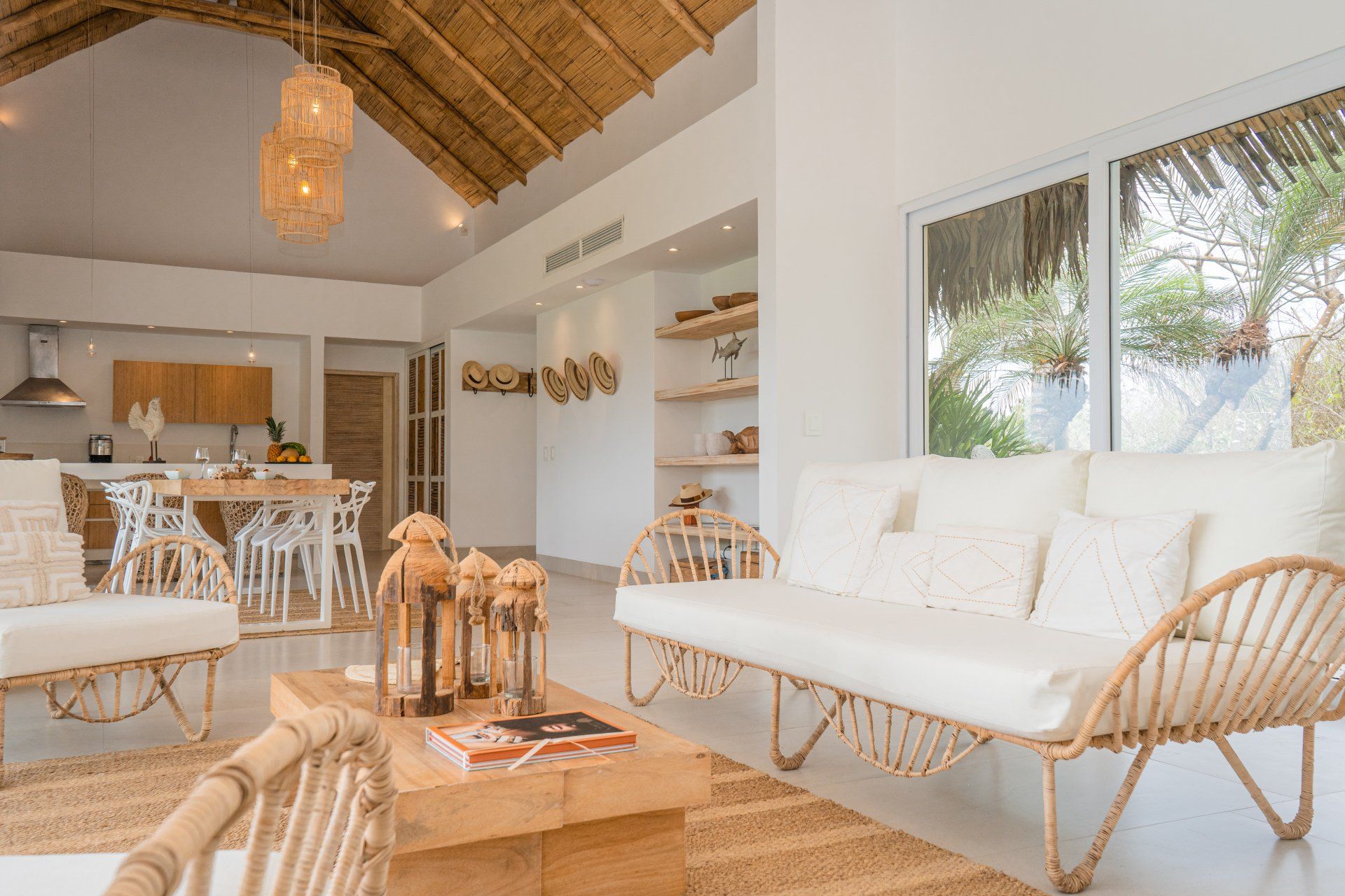 Living room with white rattan furniture, wood coffee table, and thatched roof.