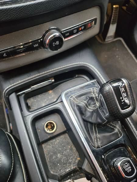 Car interior: center console with gear shift, power outlet, and control panel. Black and silver.