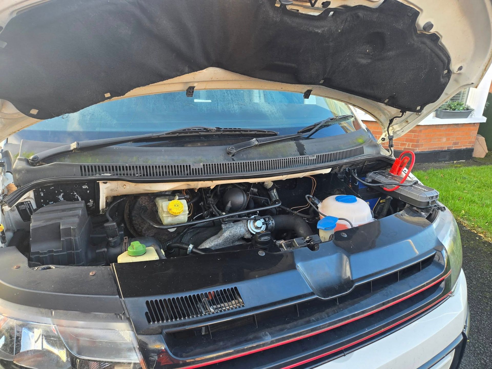 White van with its hood open, revealing the engine.
