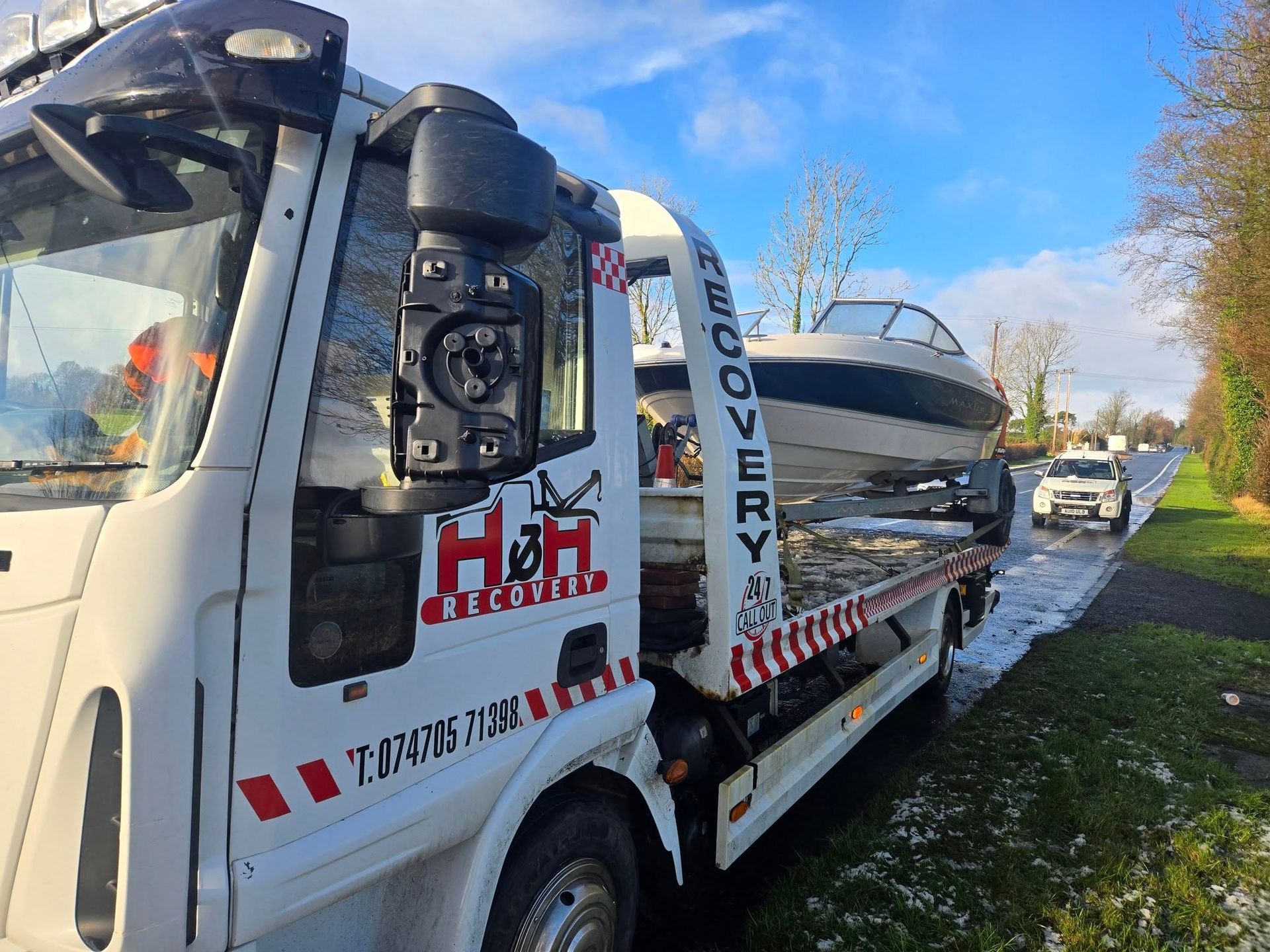 Boat on a trailer being transported on a road.