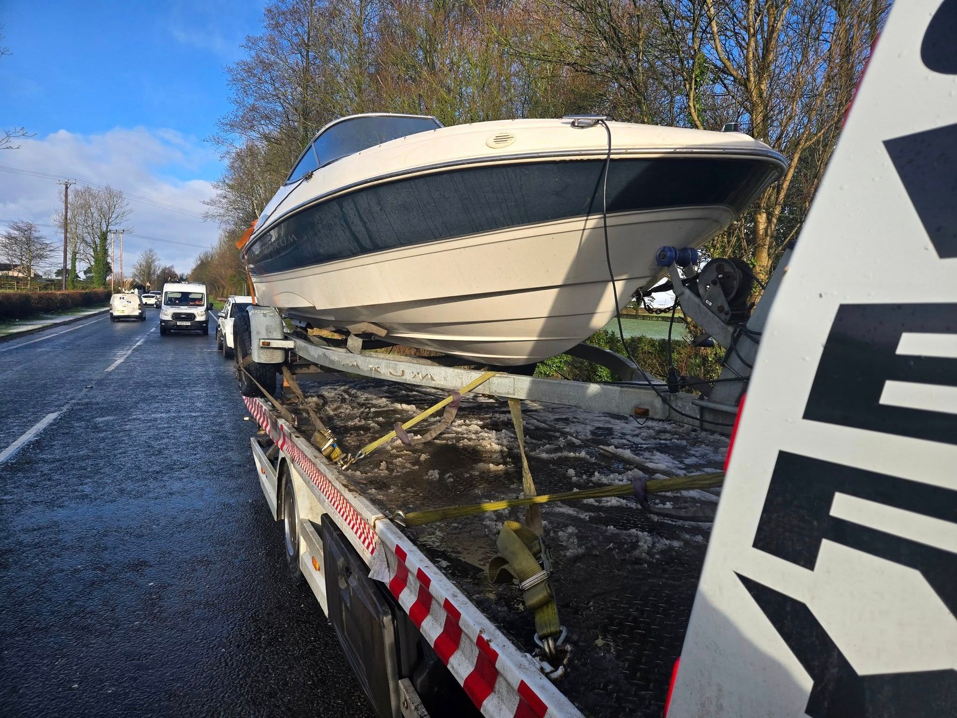 Boat on a trailer being transported on a road.