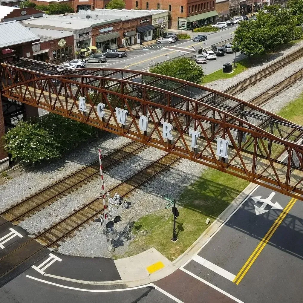 Rust-colored pedestrian bridge over railroad tracks in downtown Newburyport, with streets and buildings nearby