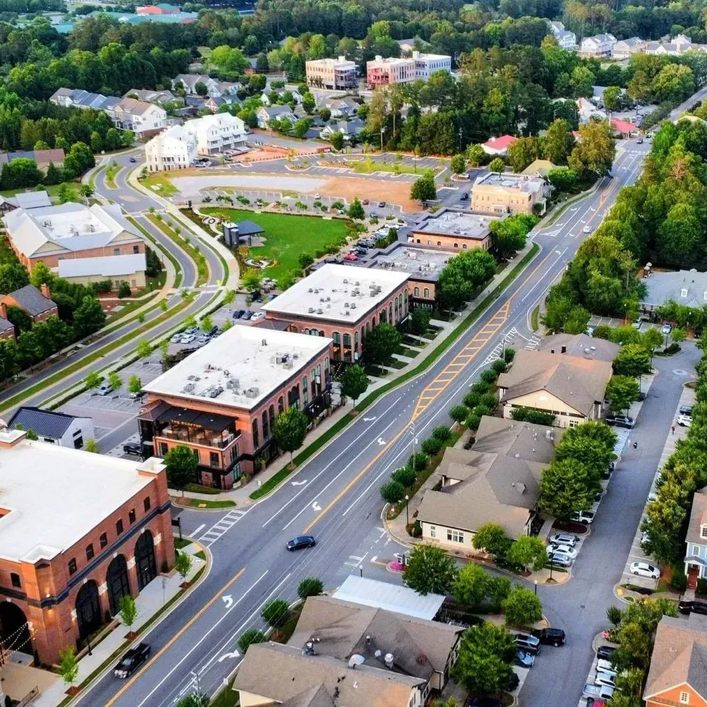 Aerial view of a suburban neighborhood with roads, brick buildings, houses, and trees