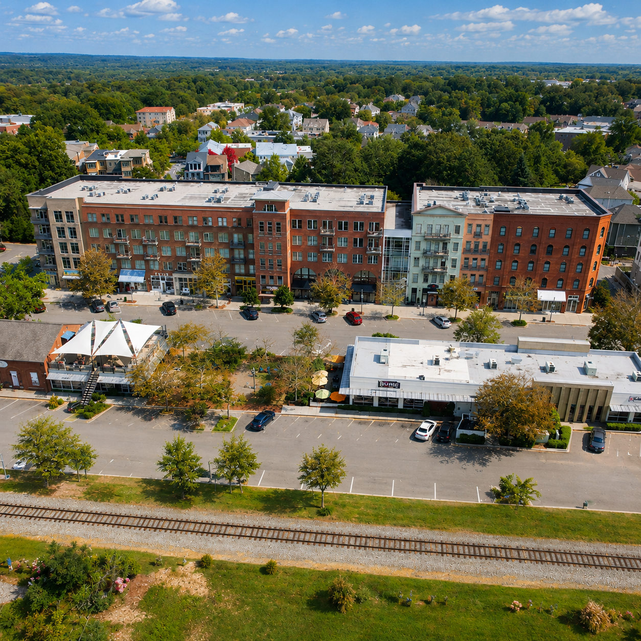Aerial view of red-brick apartment buildings amid dense green trees under a cloudy sky.