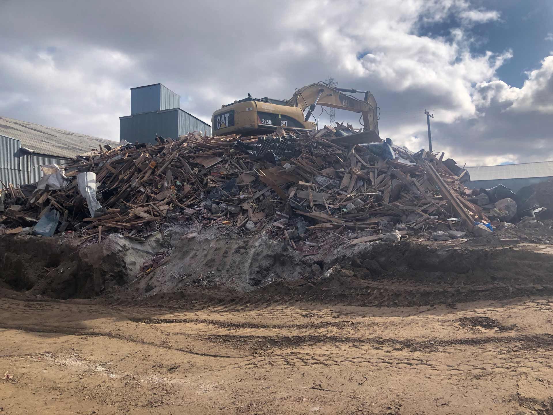 Large pile of rubble and twisted debris at a demolition site under a cloudy sky