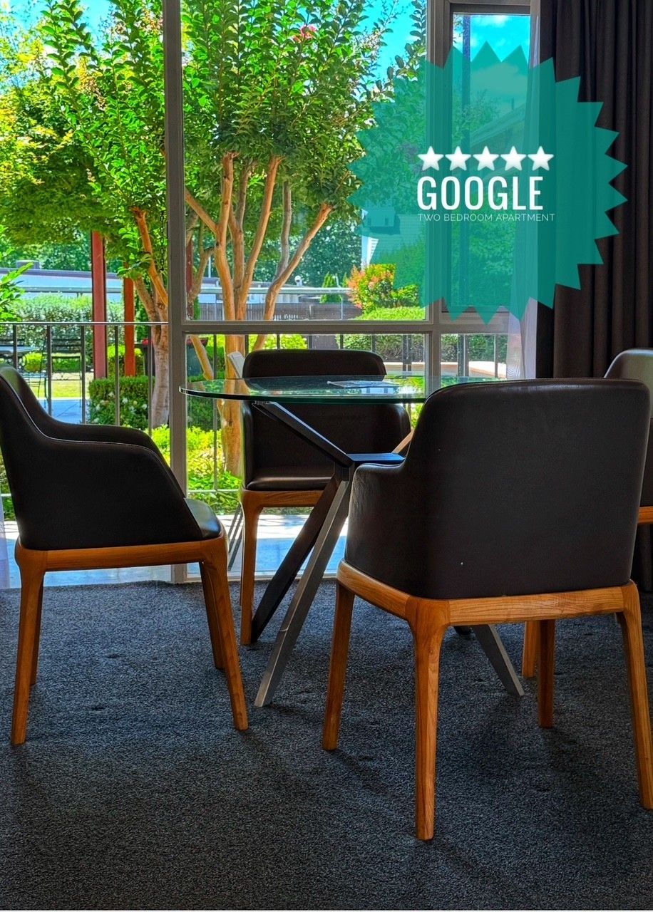 Quiet office lounge with black chairs, glass table, and a Google logo on the window.