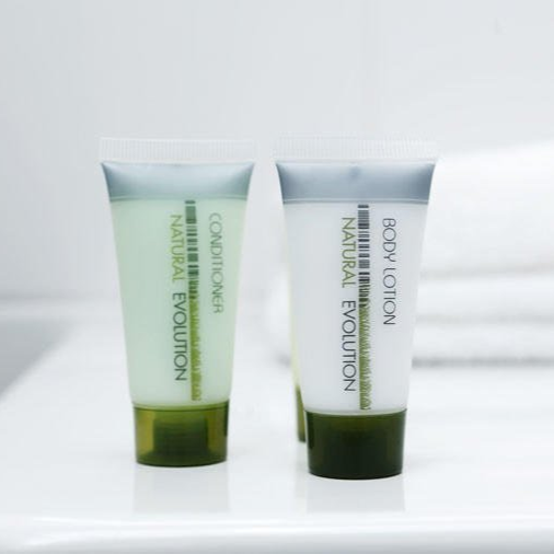Two green cosmetic tubes on a white surface against a light background