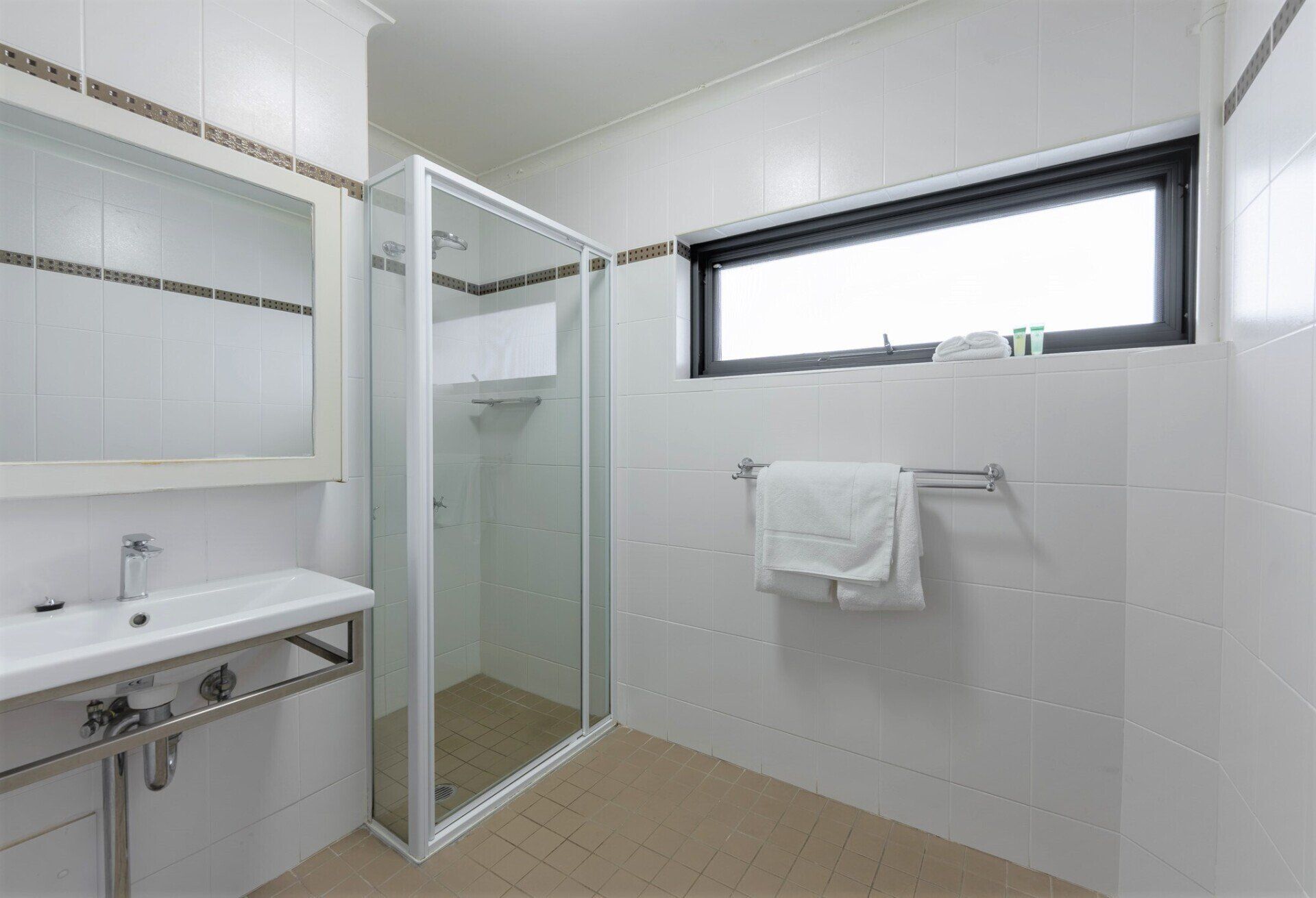 Modern white bathroom with sink, shower, window, and towel rack