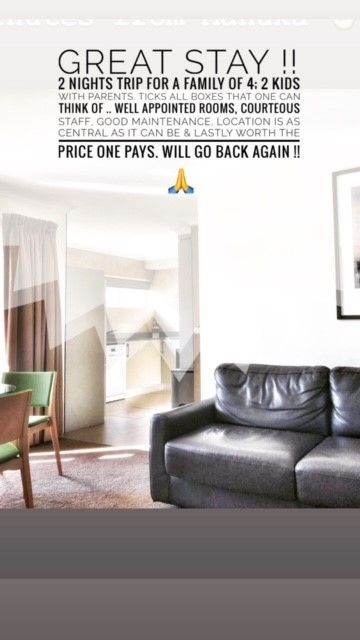 Living room with black leather sofa, white armchairs, and large “Great Stay!!” rental promo text above