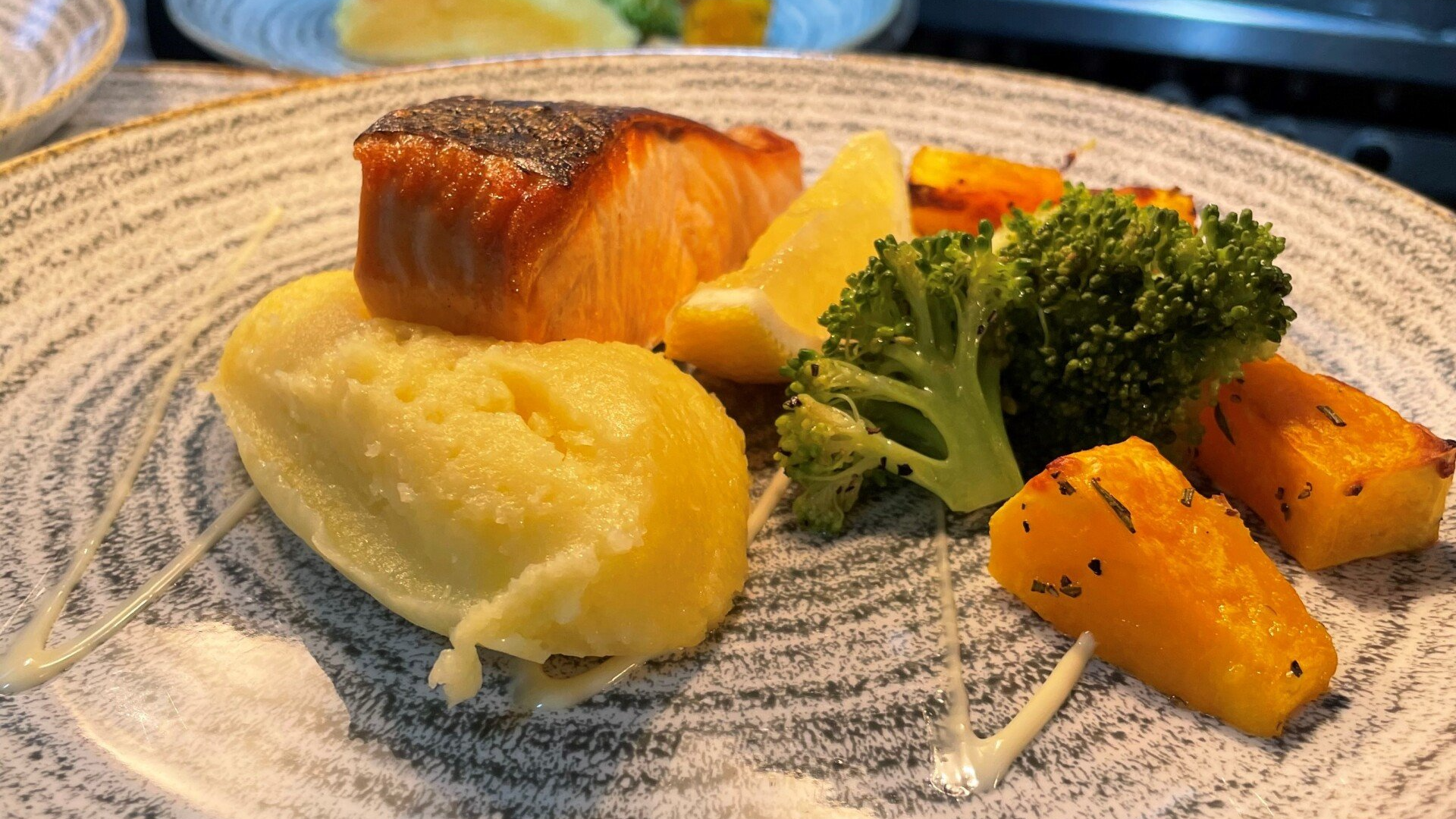 Plated meal with salmon, mashed potatoes, broccoli, and roasted carrots on a white plate