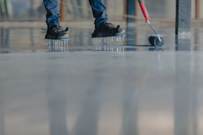 Person mopping a glossy floor with a red-handled mop, seen from the knees down.