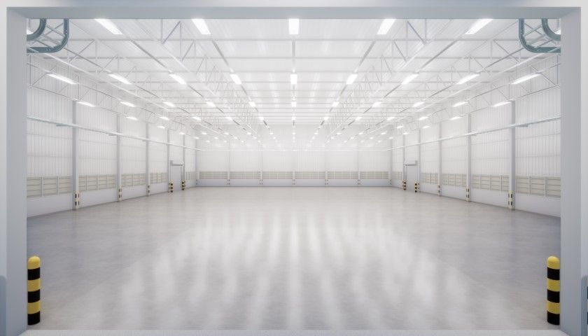 Empty white industrial warehouse interior with polished floor and overhead lights