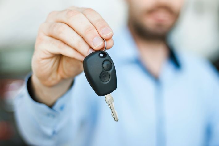 Uomo che porge le chiavi di un'auto con un telecomando nero.