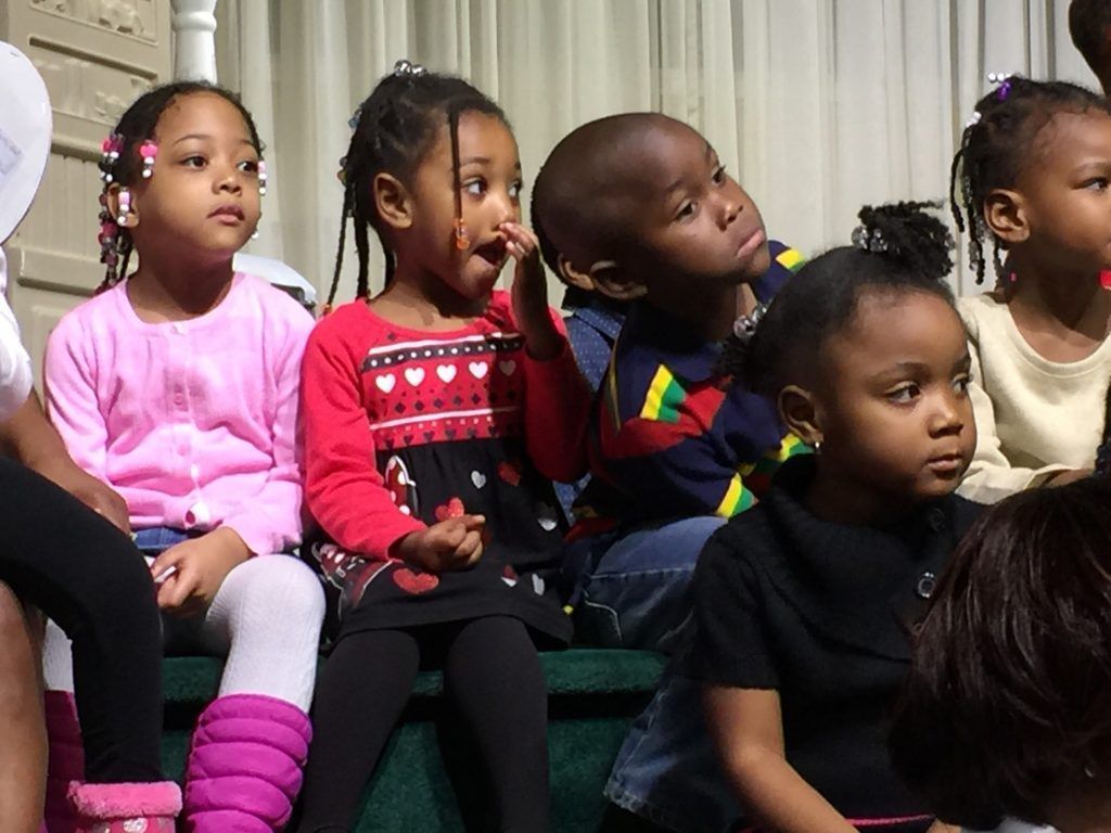A group of children are sitting on a staircase looking at something
