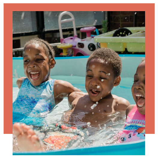 Three children are swimming in a pool and smiling.