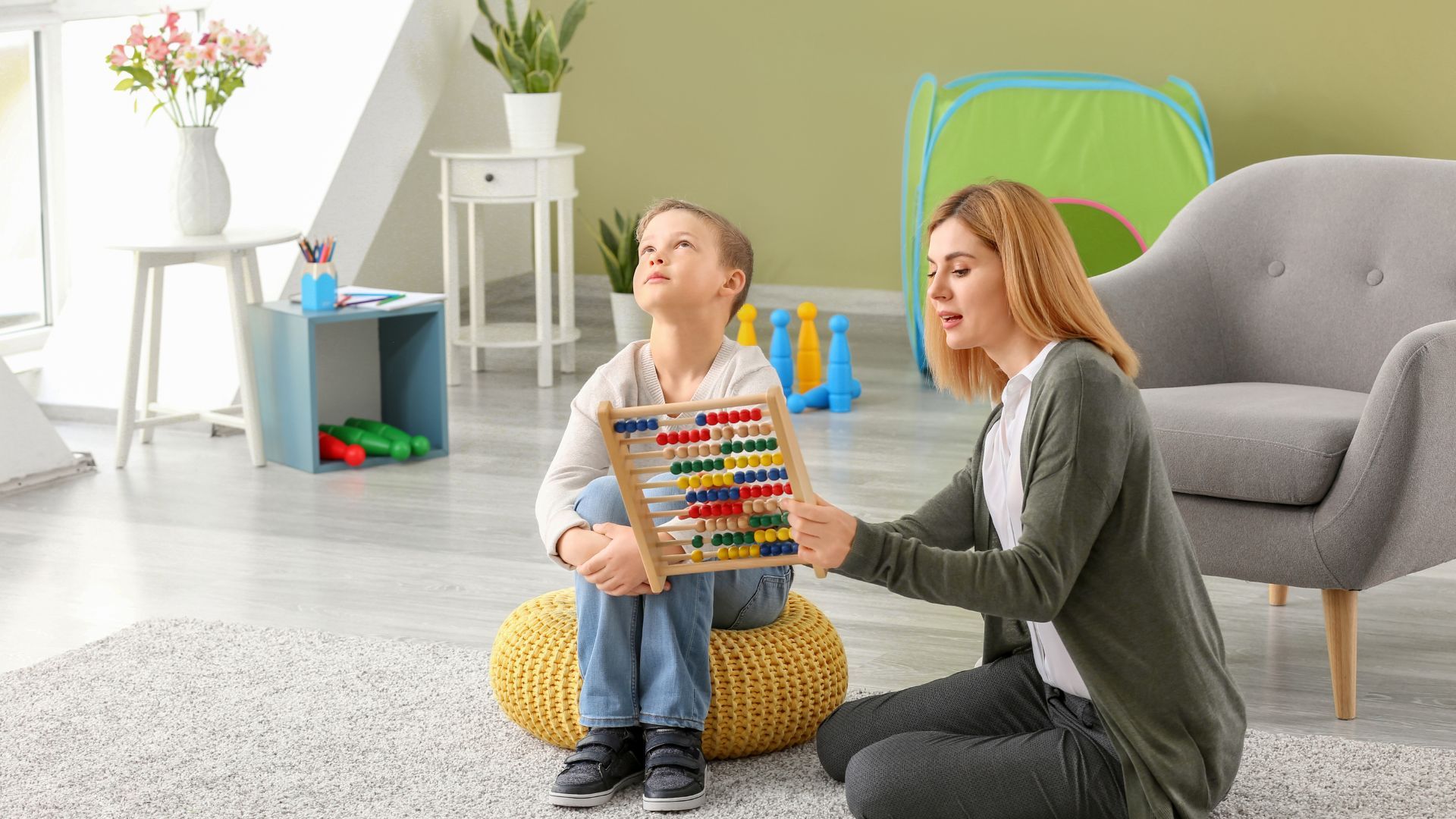 Eine Erzieherin kommuniziert mit einem Kind mit Autismus über einen Rechenschieber.