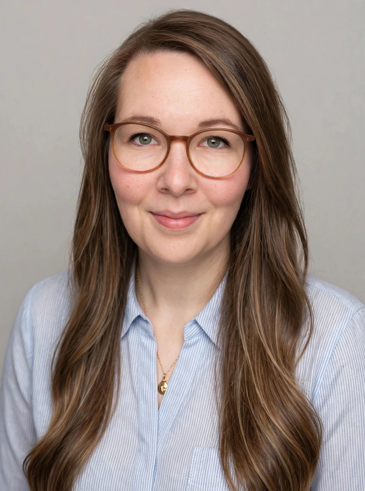 Eine Frau mit langen braunen Haaren lächelt in die Kamera