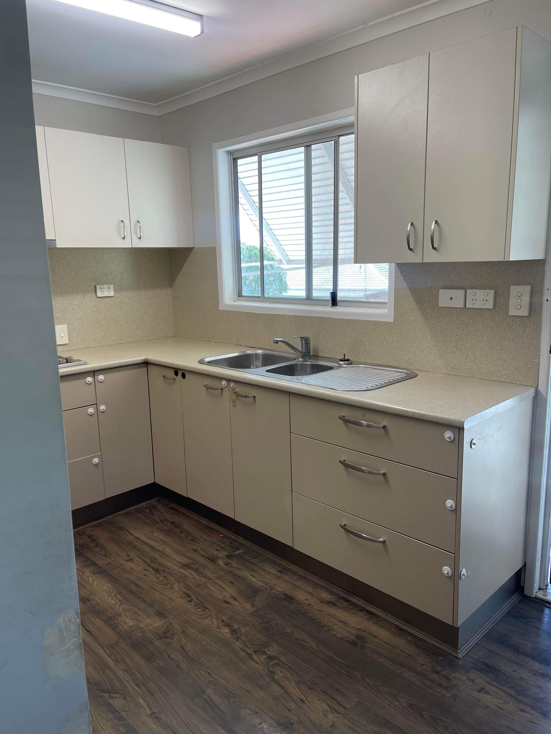 a kitchen with white cabinets , a sink , and a window .