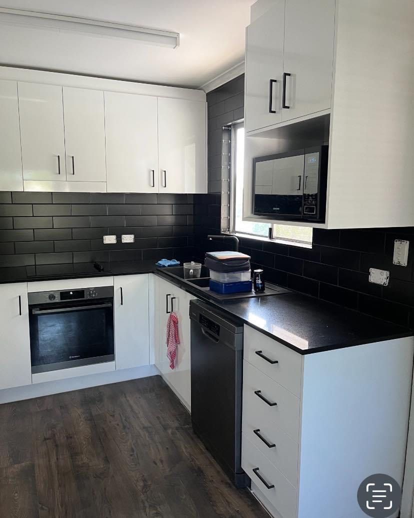 a kitchen with white cabinets and black counter tops