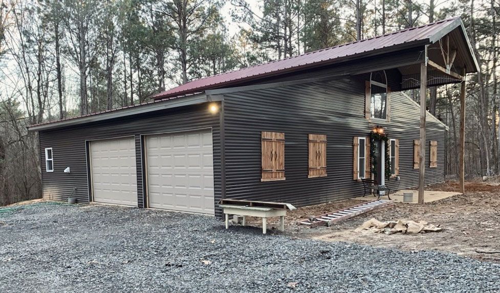 A large log cabin with two garage doors and a red roof.