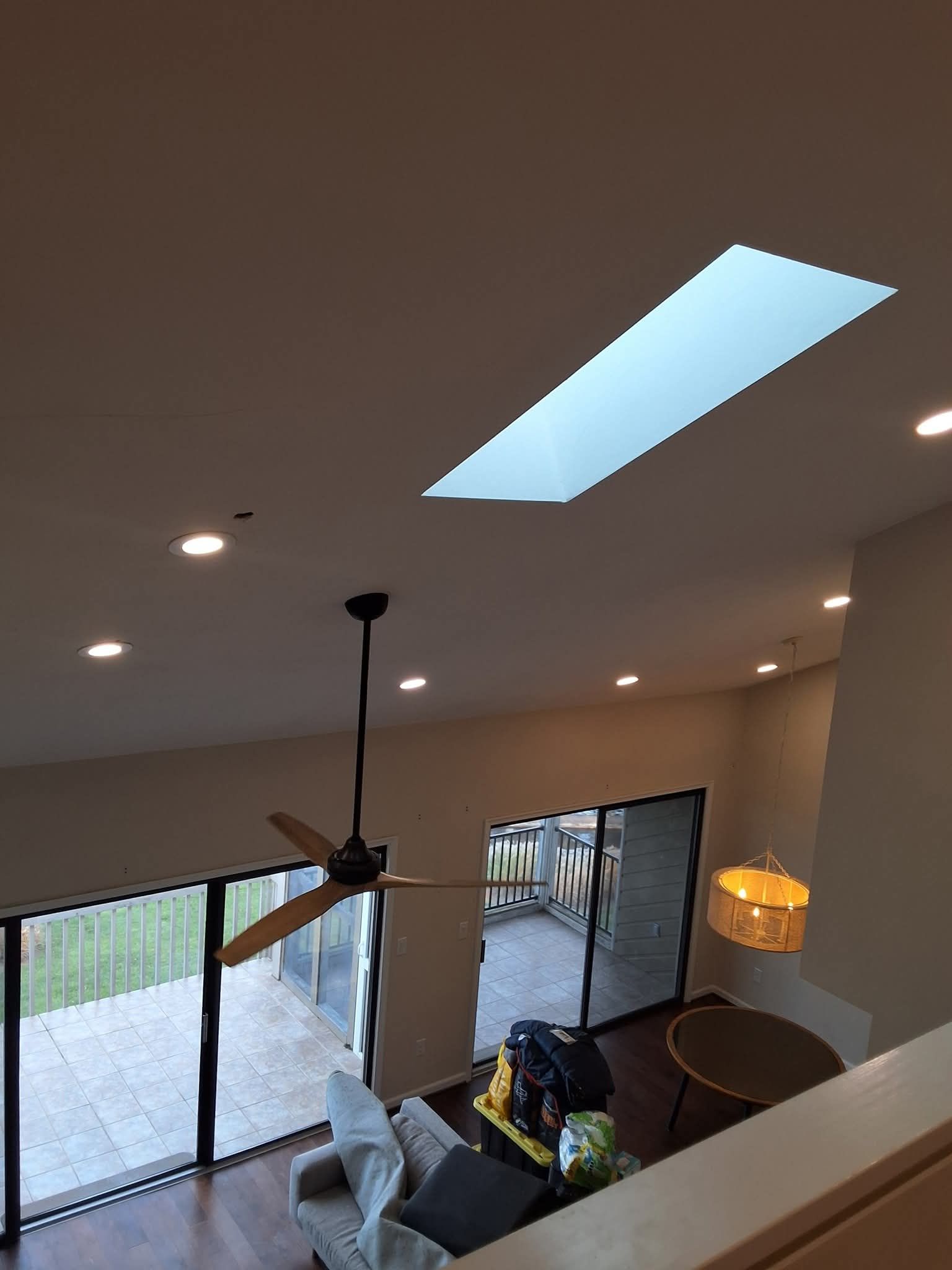 Modern living room with skylight, ceiling fan, sliding glass doors, and patio view
