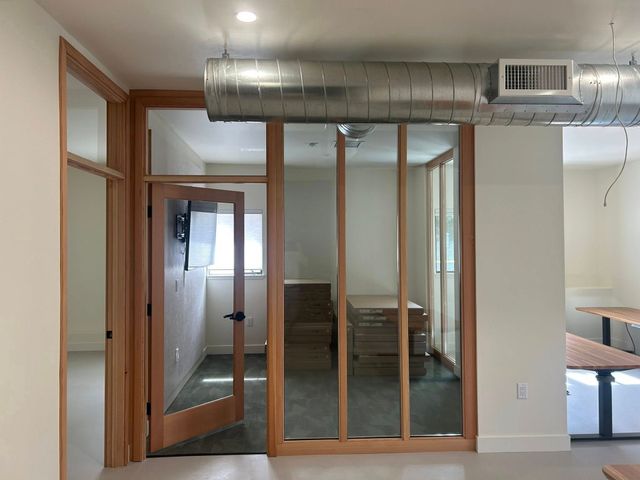 Interior room undergoing renovation, with exposed wooden framing and debris on the floor.