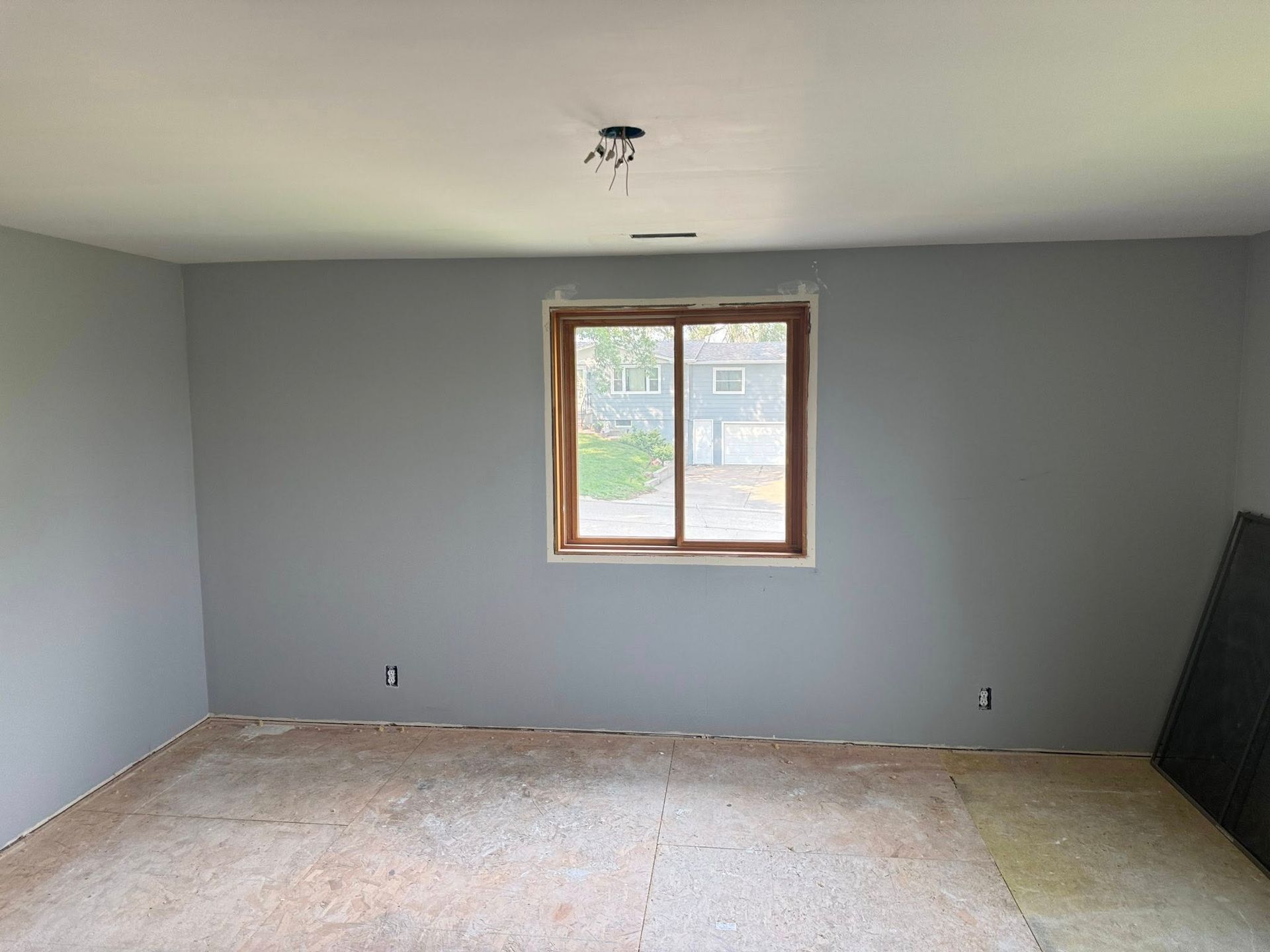 Empty room with gray walls, window, and exposed flooring.
