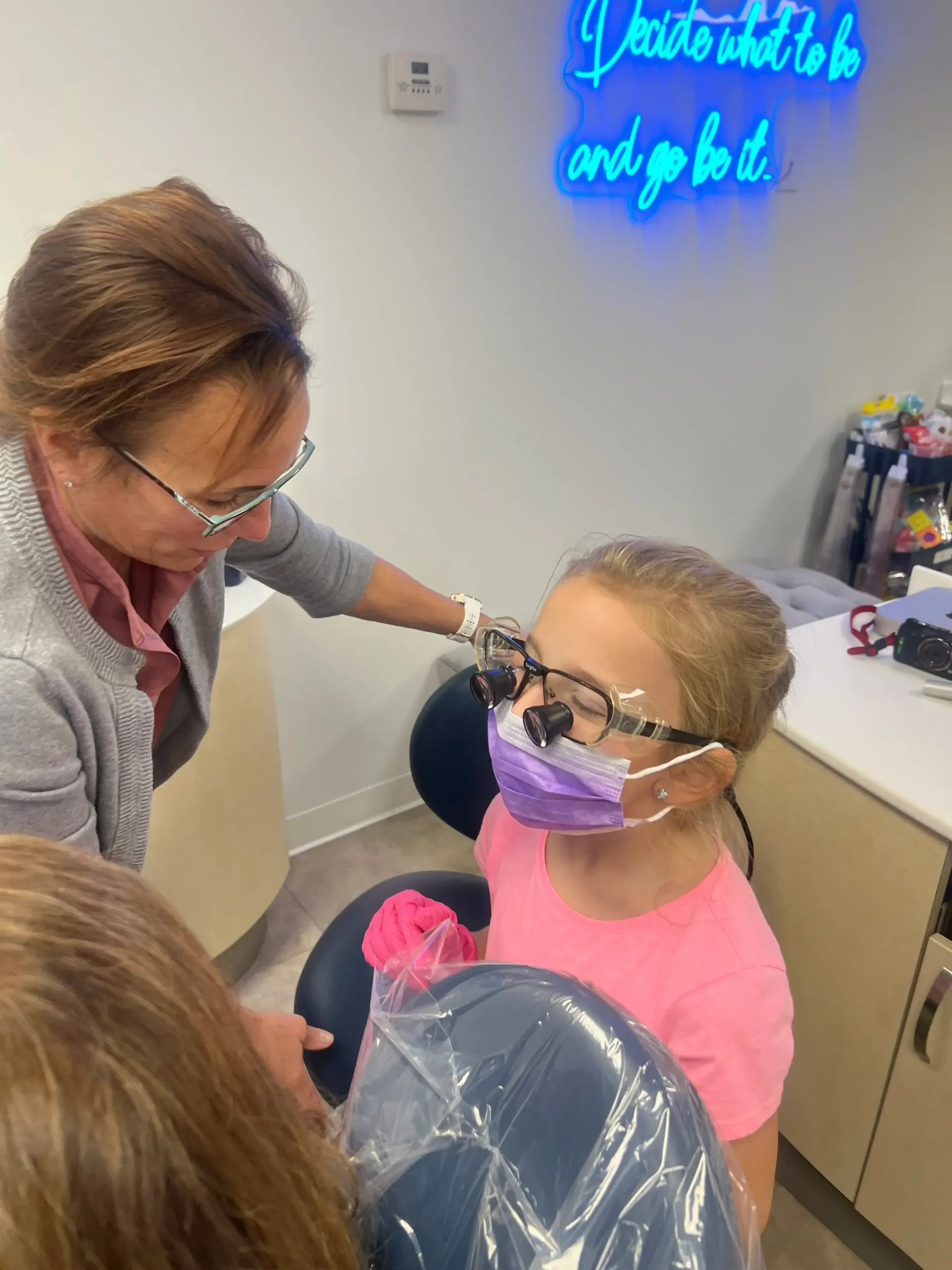 Young girl trying on dental loupes during an orthodontic visit.