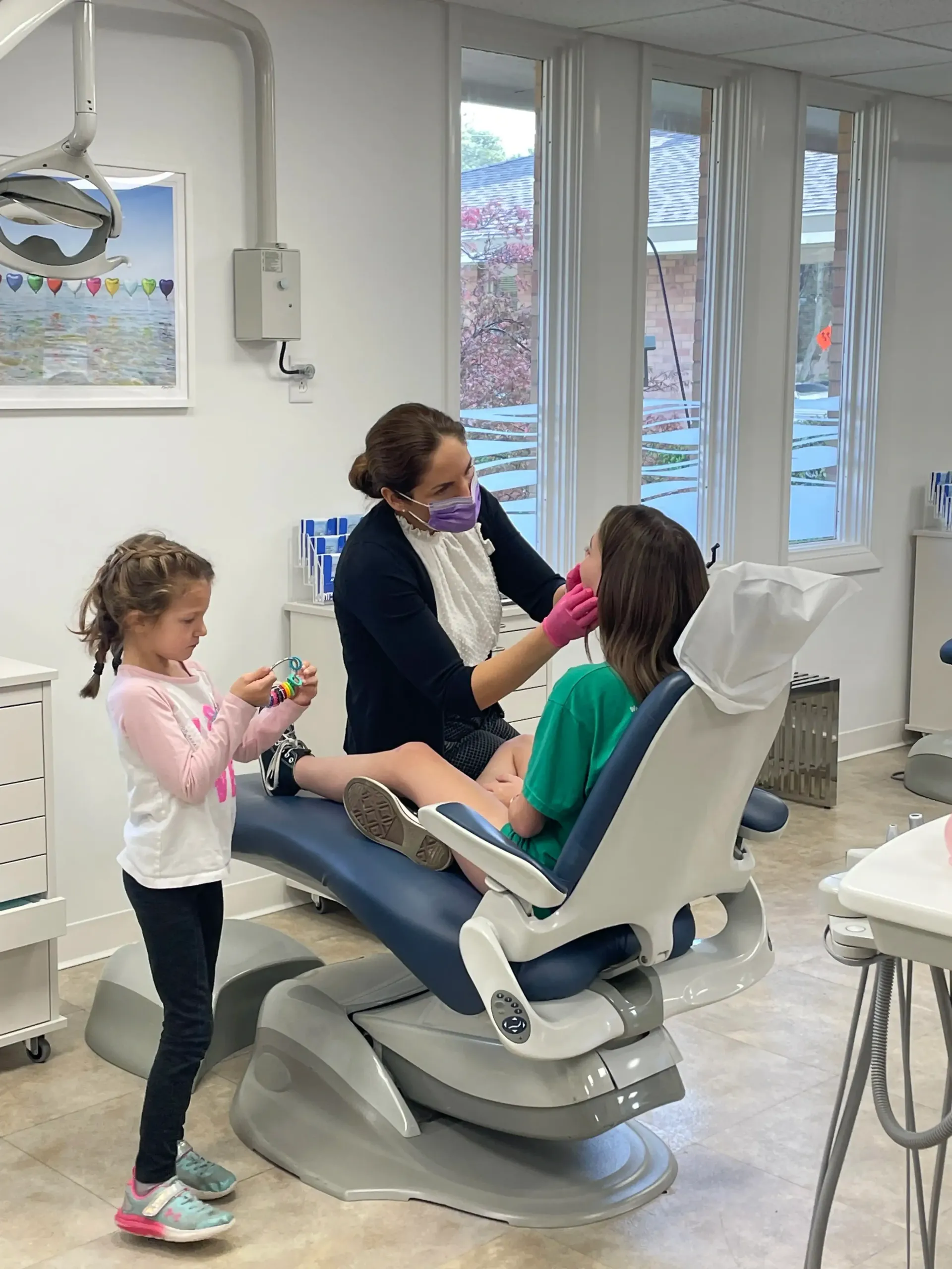 Dr. Sarah examining a young patient in a dental clinic chair.