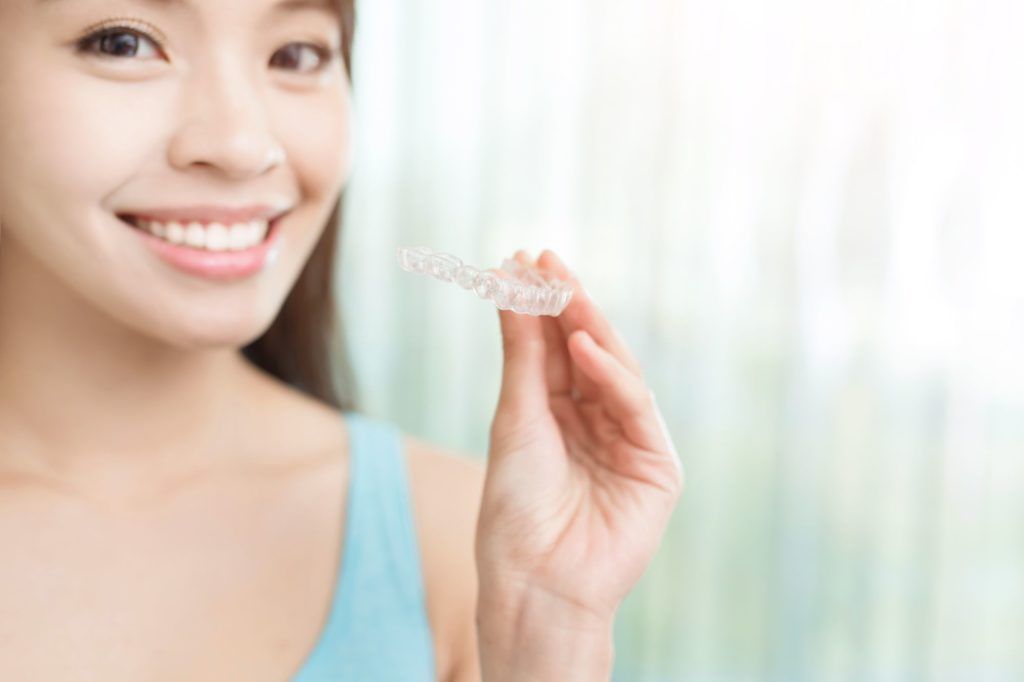 a woman is smiling while holding a clear brace in her hand .