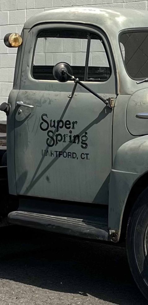 A Gray Truck Is Parked In Front Of A Brick Wall — Hartford, CT — Super Spring & Brake Co., Inc. A Gray Truck Is Parked In Front Of A Brick Wall — Hartford, CT — Super Spring & Brake Co., Inc.