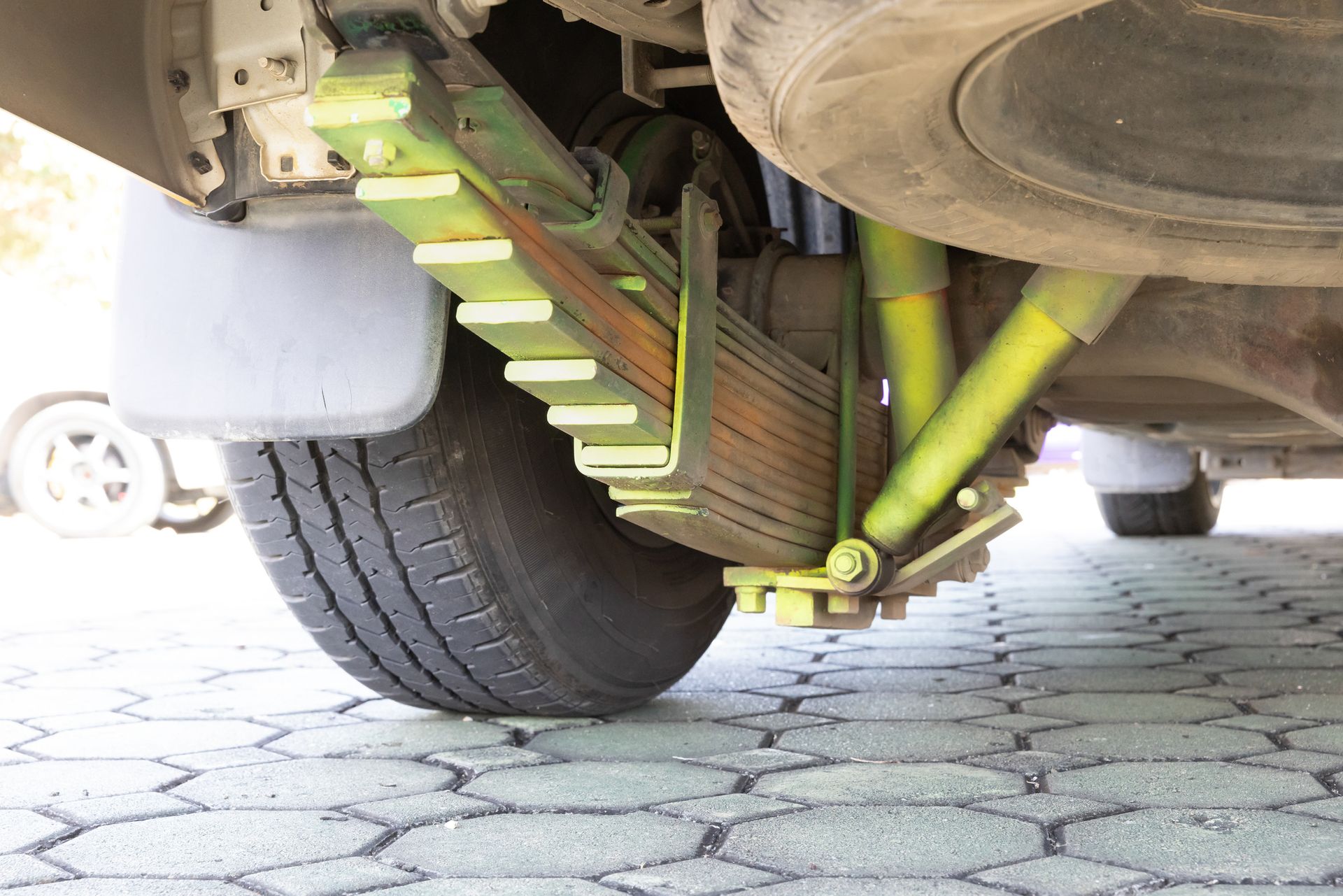 A close up of a car suspension with a tire in the background