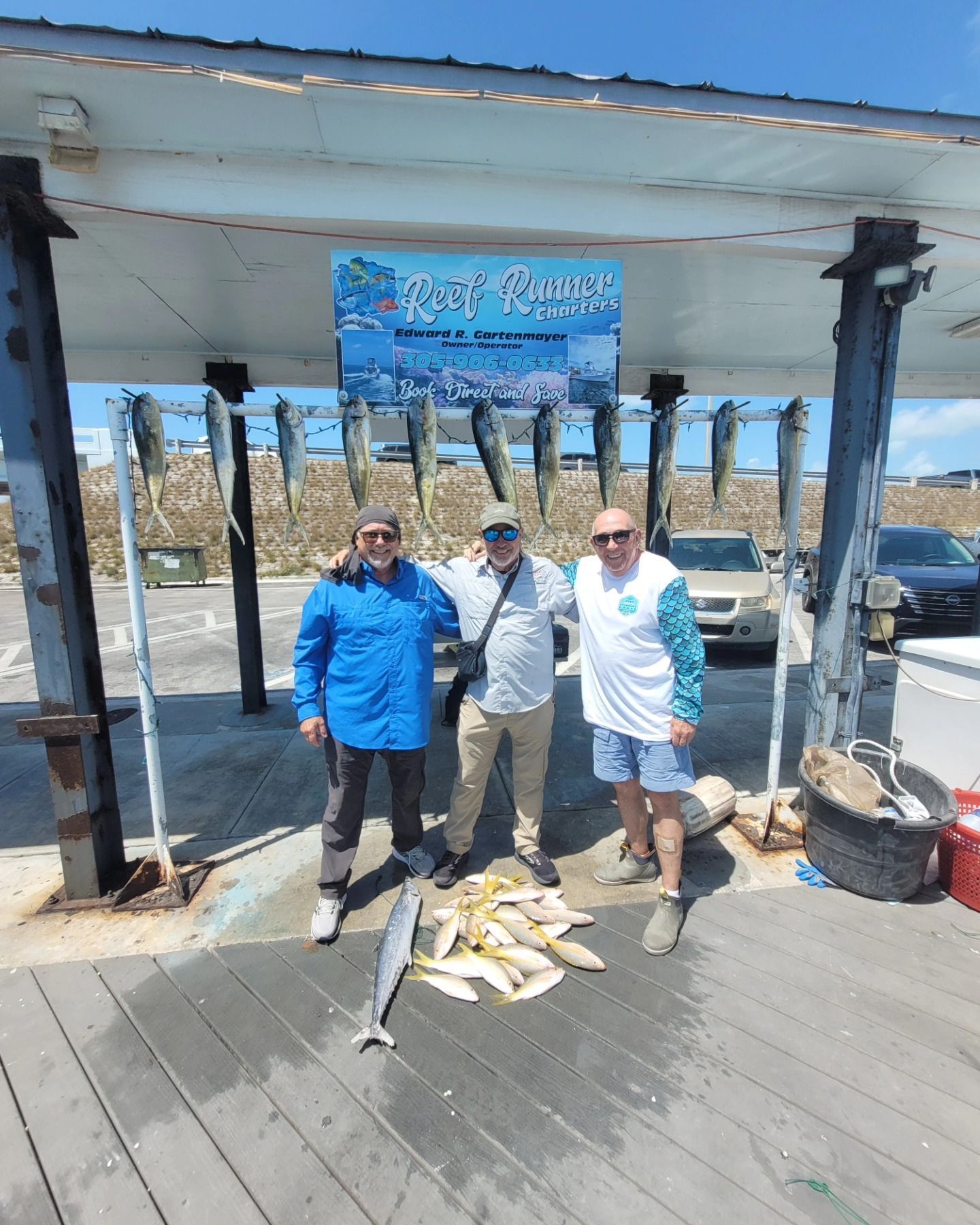 Three people stand smiling on a pier under a 