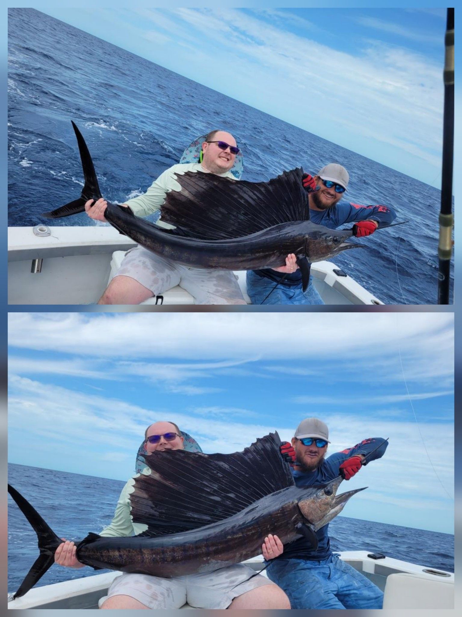 Two people on a boat hold a large sailfish up for a photo against an ocean backdrop.
