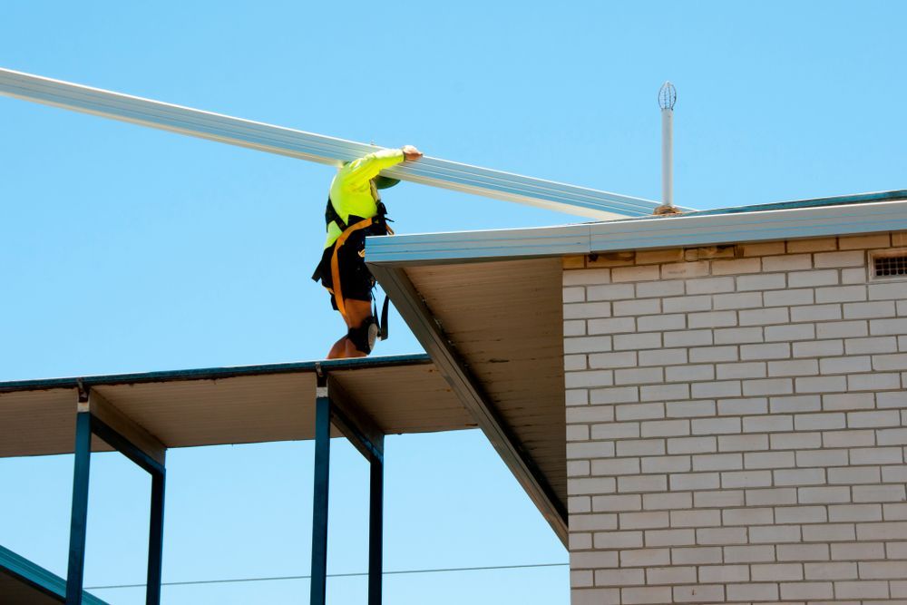 Construction Worker on Roof With Metal Beam, Blue Sky — Rowal Constructions in Lake Macquarie, NSW