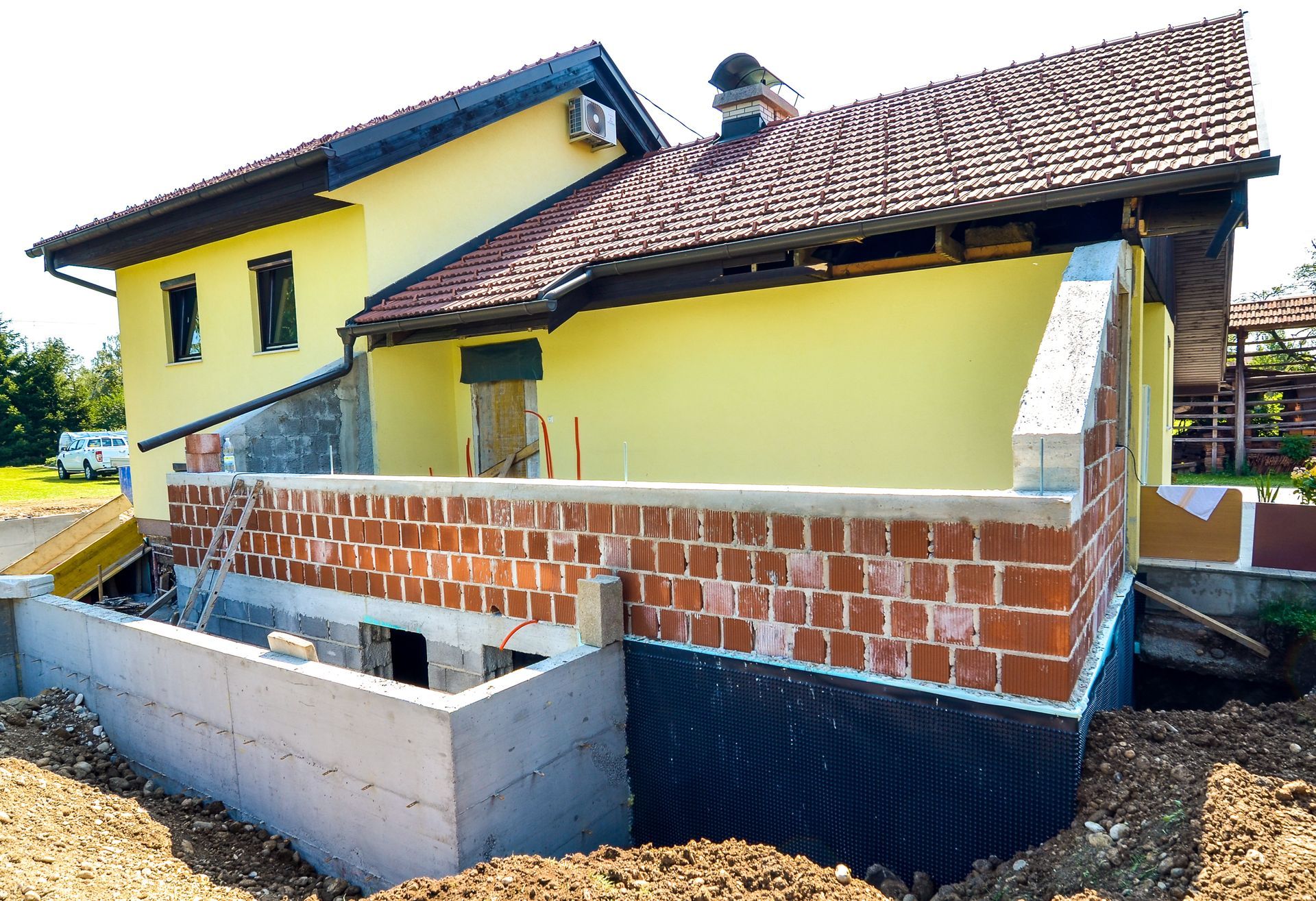 House Under Construction With Red Brick Wall and Yellow Siding — Rowal Constructions in Newcastle, NSW