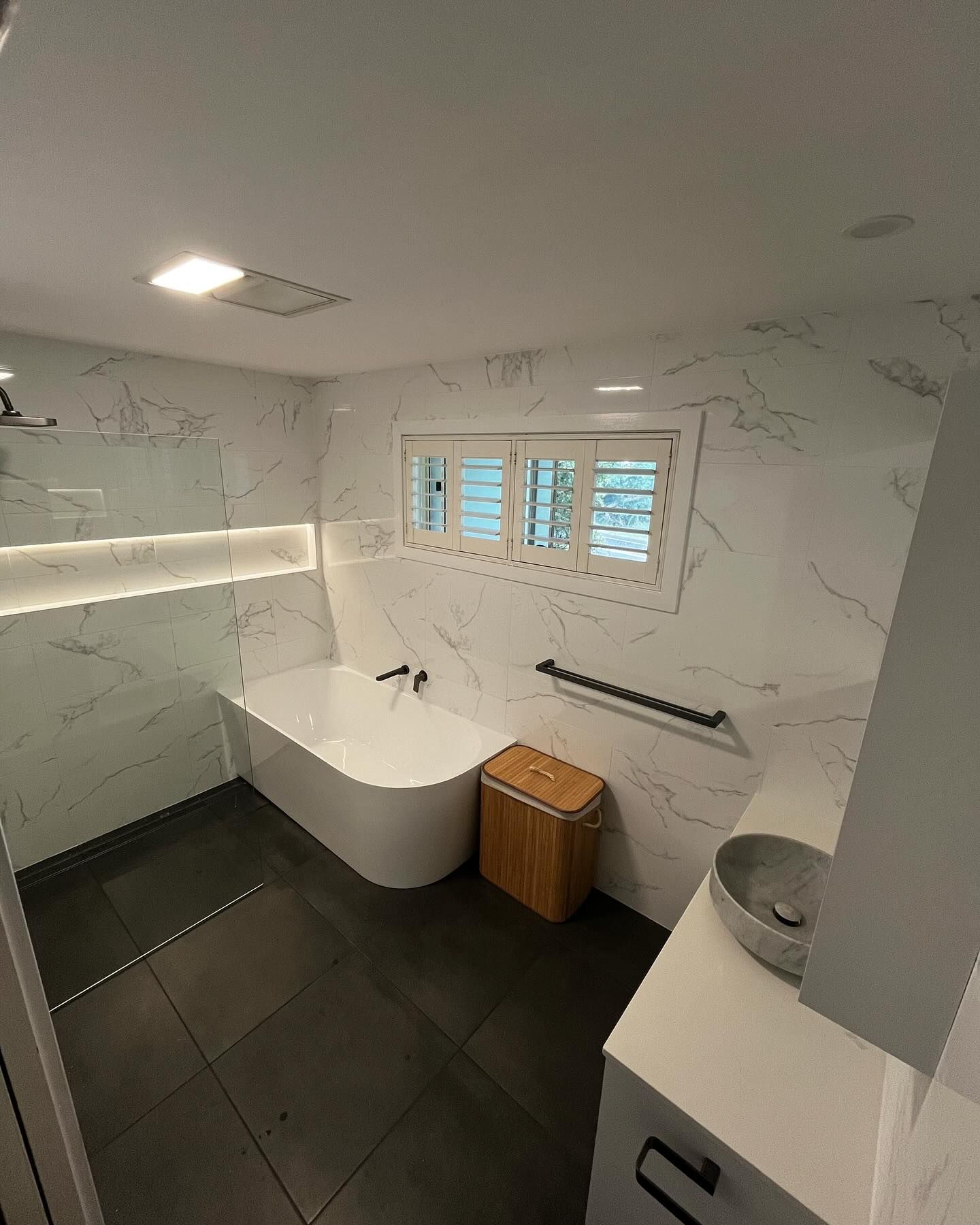 Modern bathroom with marble-look tile, a freestanding tub, and a vanity.
