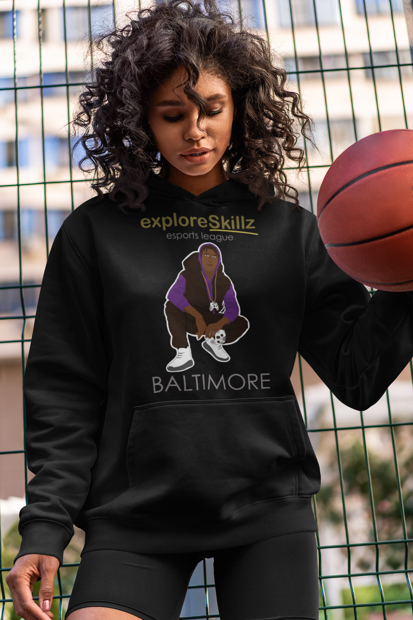 A woman wearing a black hoodie is holding a basketball.