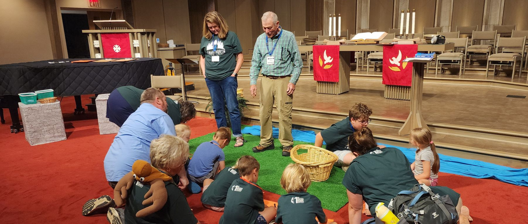 Adults and Children gathered in the Sanctuary learning a Bible Story. 