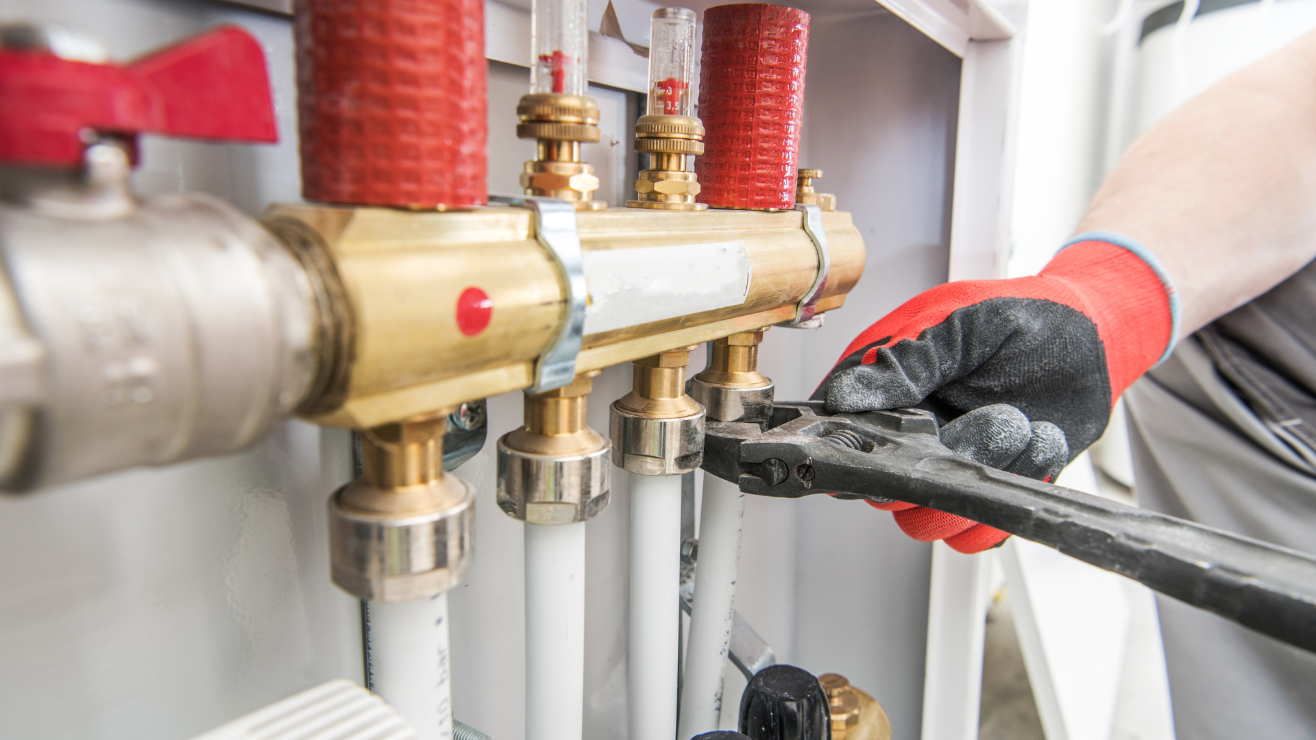 A plumber is working on a heating system with a wrench.