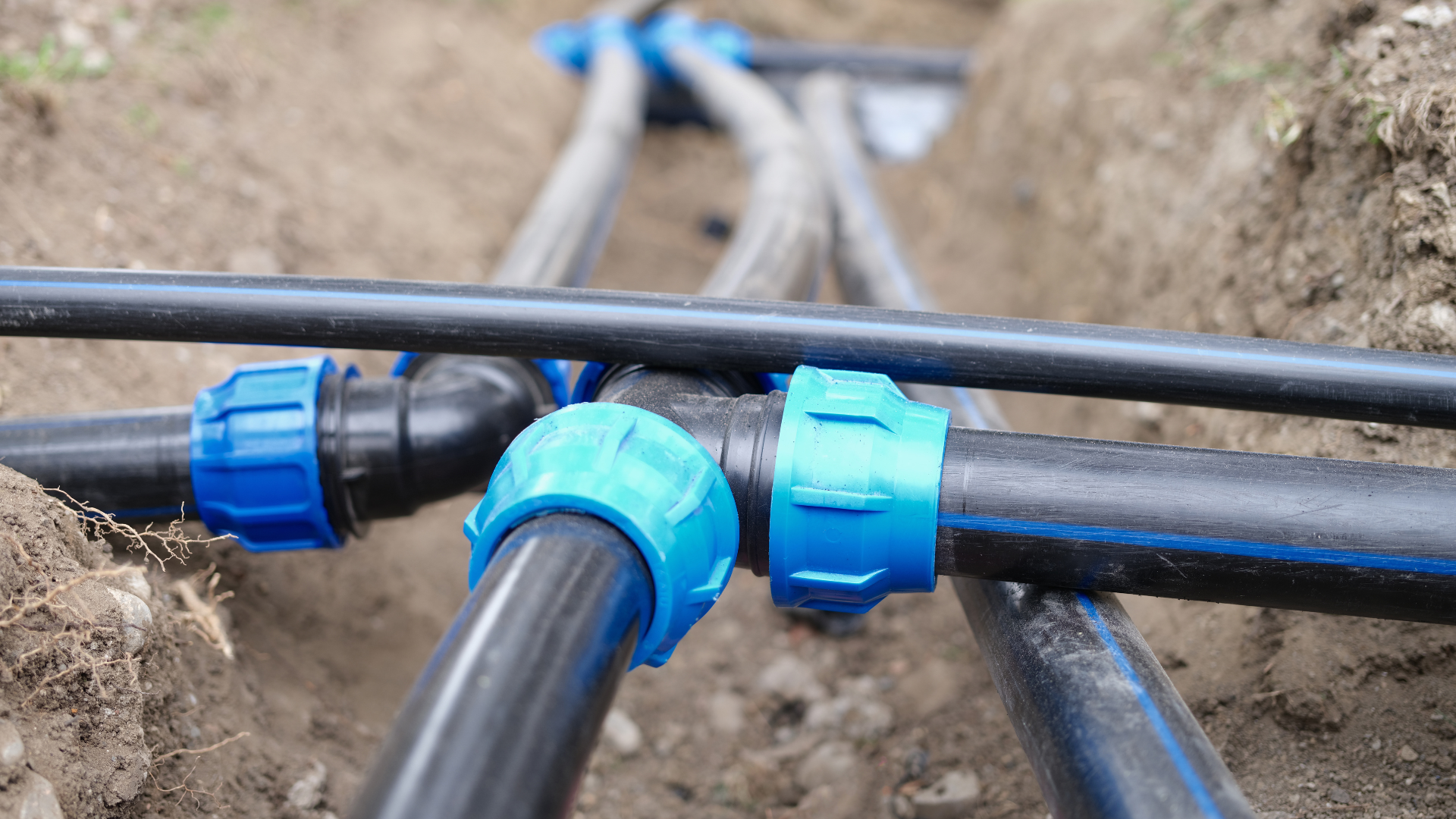 A bunch of water pipes are connected to each other in the dirt.