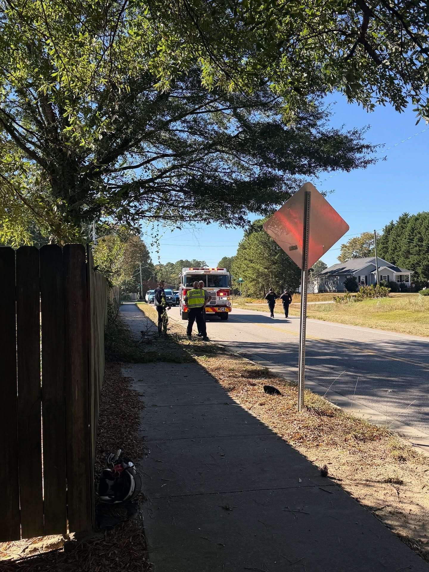 Workers and a utility truck on a sunny street beside a sidewalk and orange road sign