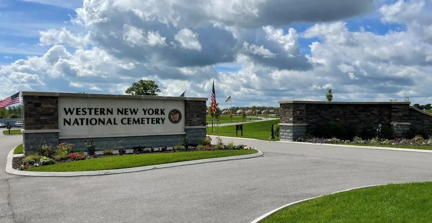 Entrance sign for Western New York National Cemetery on a sunny day with cloudy sky