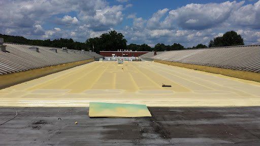 Empty outdoor stadium field covered with yellow tarp under a cloudy sky