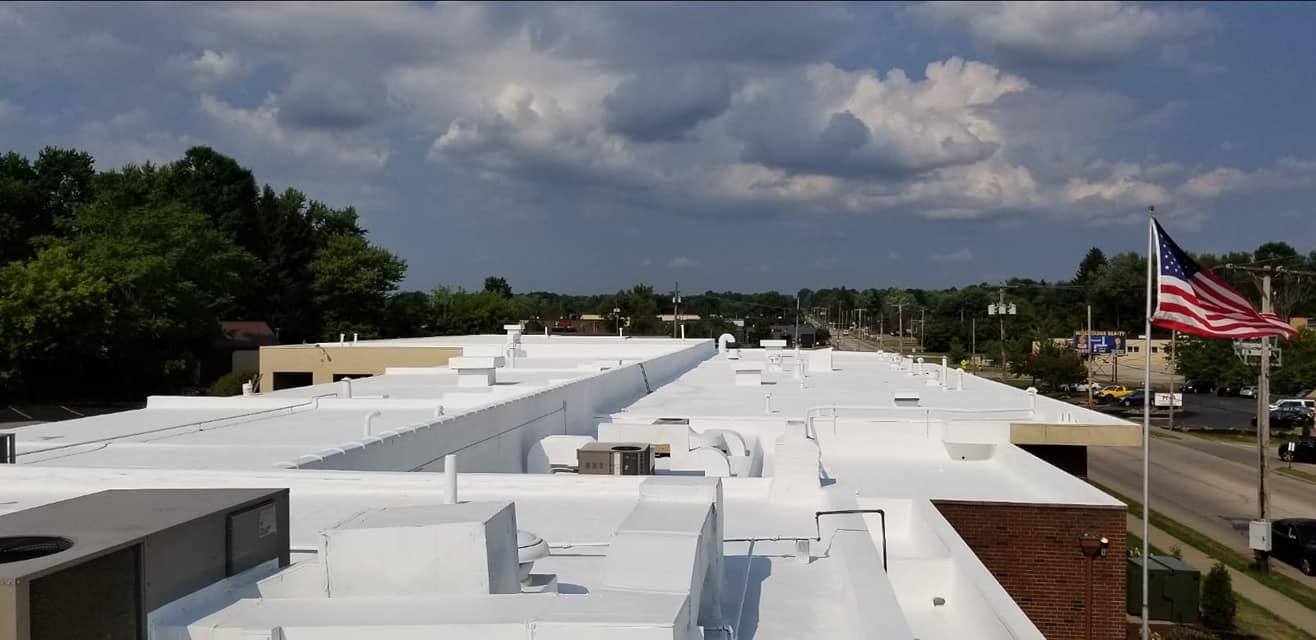 Rooftop view of a white flat-roofed building with an American flag under cloudy skies