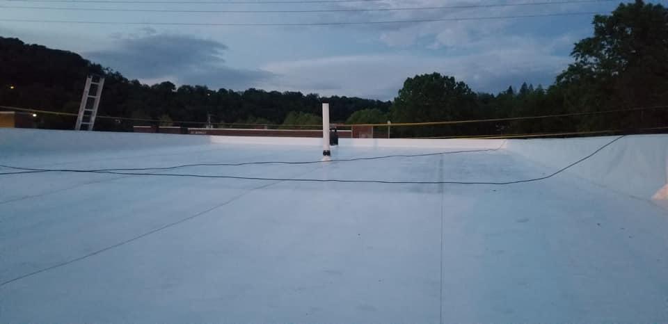 Empty white-roofed structure at dusk with trees and cloudy sky in the background