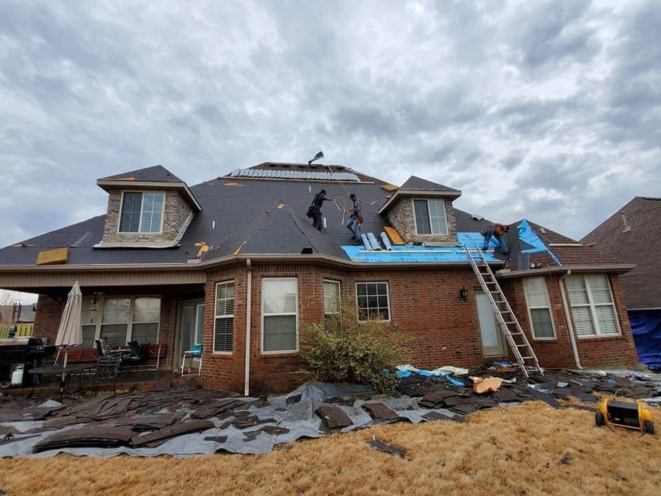 A large brick house is being remodeled with a new roof.