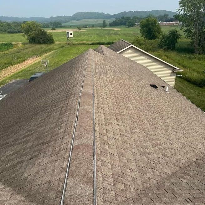 an aerial view of a house 's roof with a field in the background