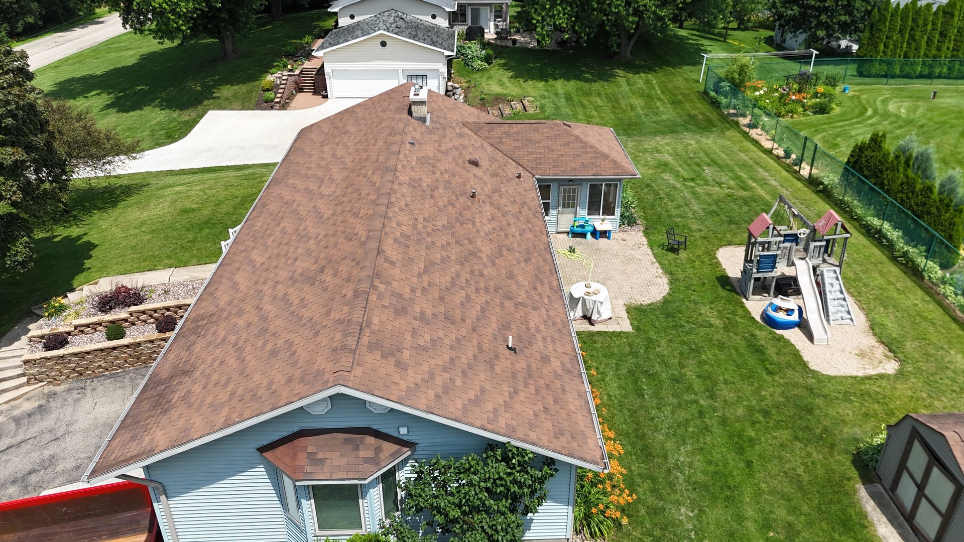 An aerial view of a house with a brown roof and a large yard.